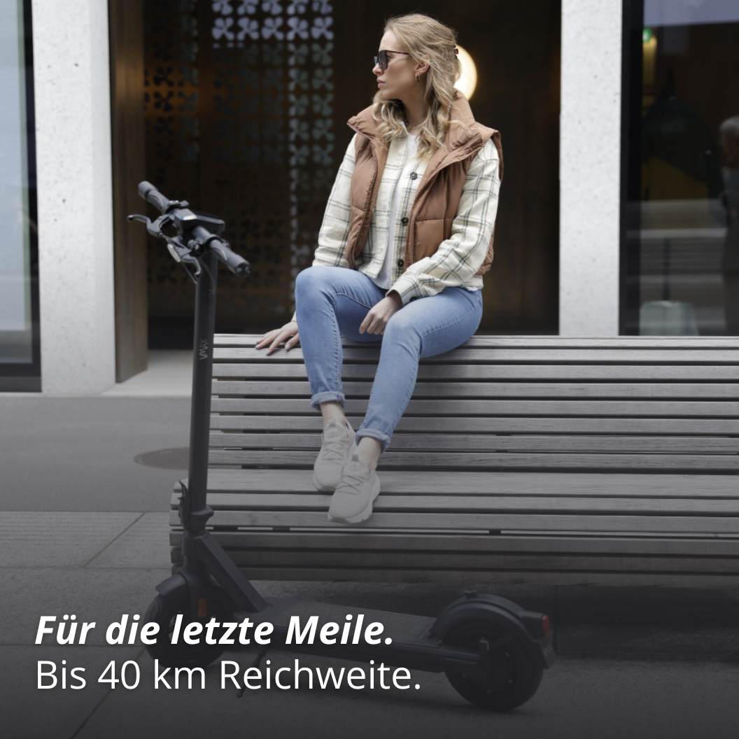 Frau sitzt auf einer ank, vor ihr steht ein VMAX E-Scooter