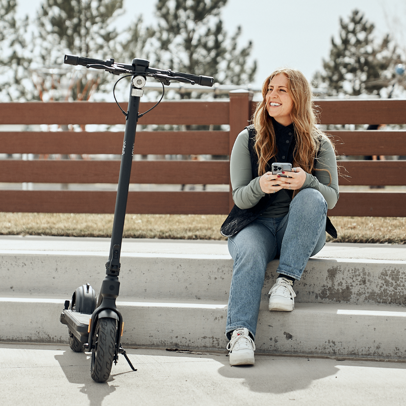 Frau sitzt neben VMAX E-Scooter